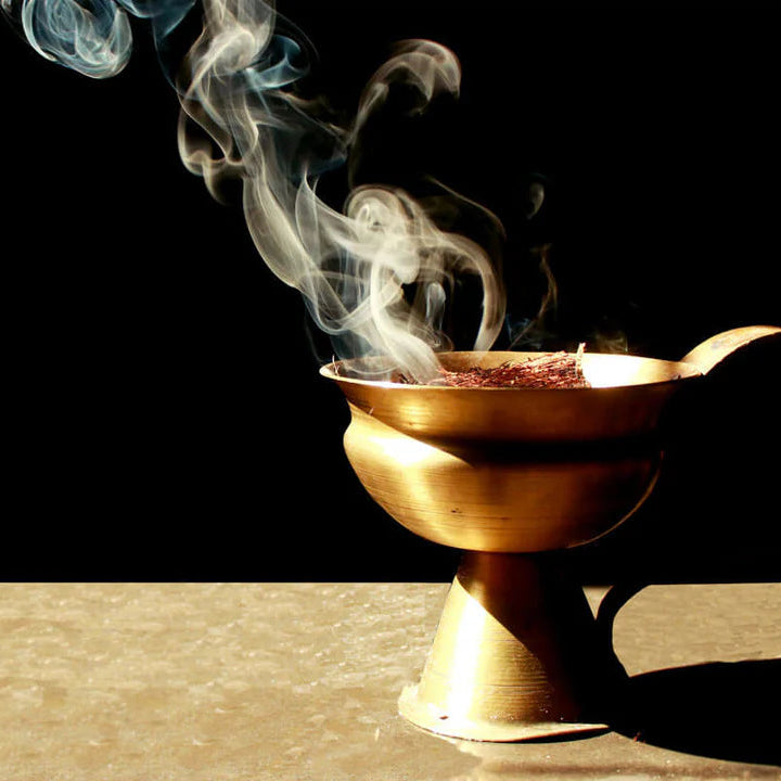 Bronze incense burner with smoke on a dark background